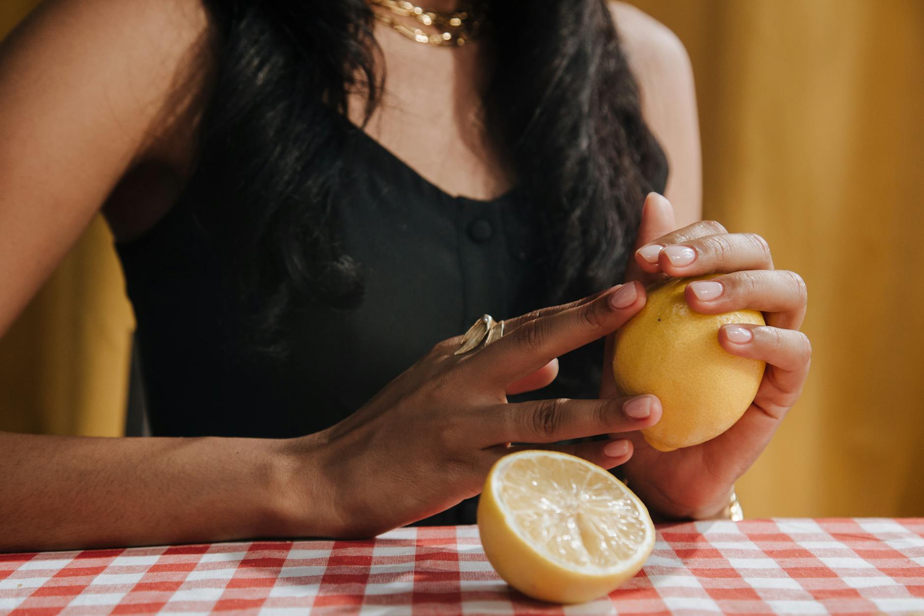 Woman holding a fresh lemon against a neutral background, symbolizing citrus freshness and clarity