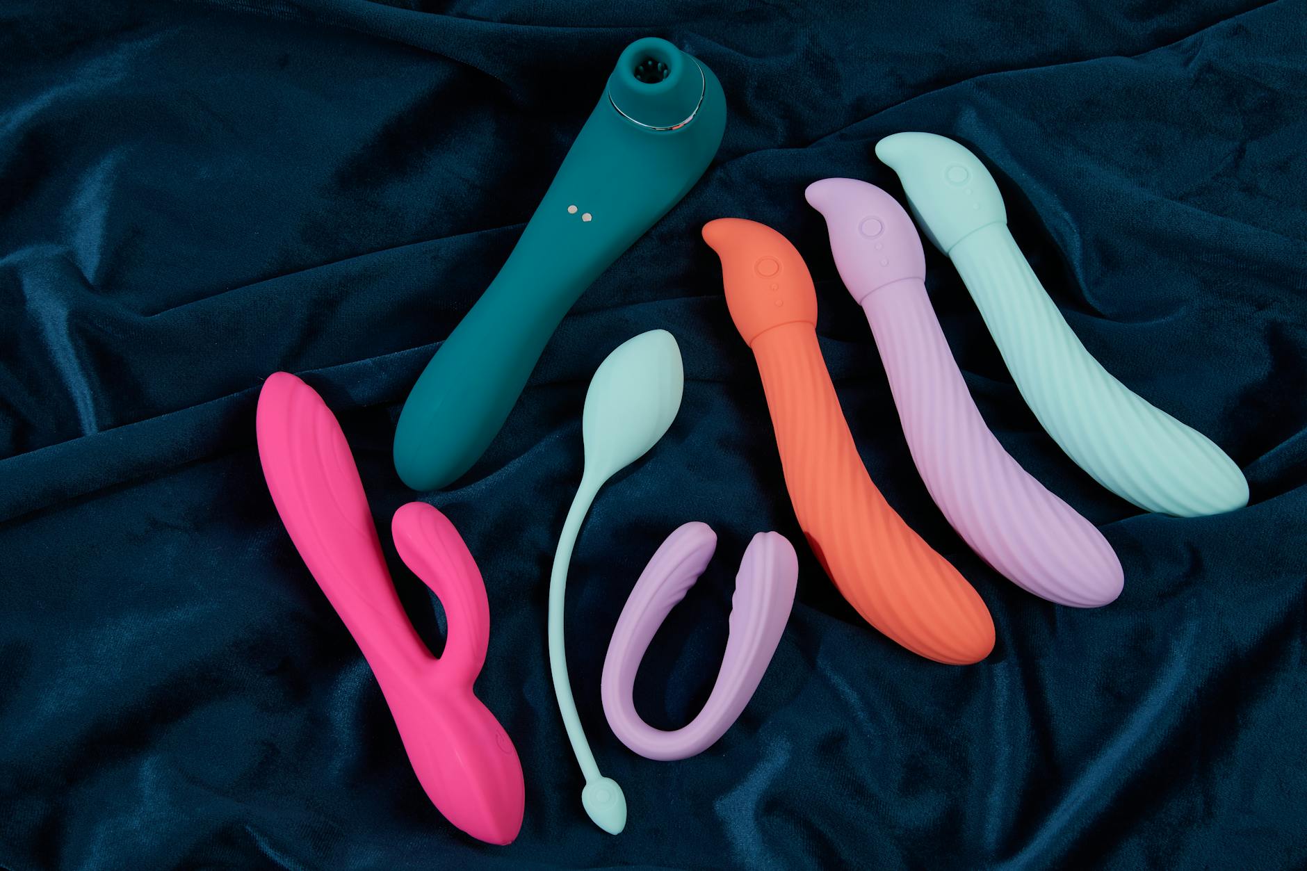 Hand holding a vibrator against a purple backdrop, representing modern pleasure tools