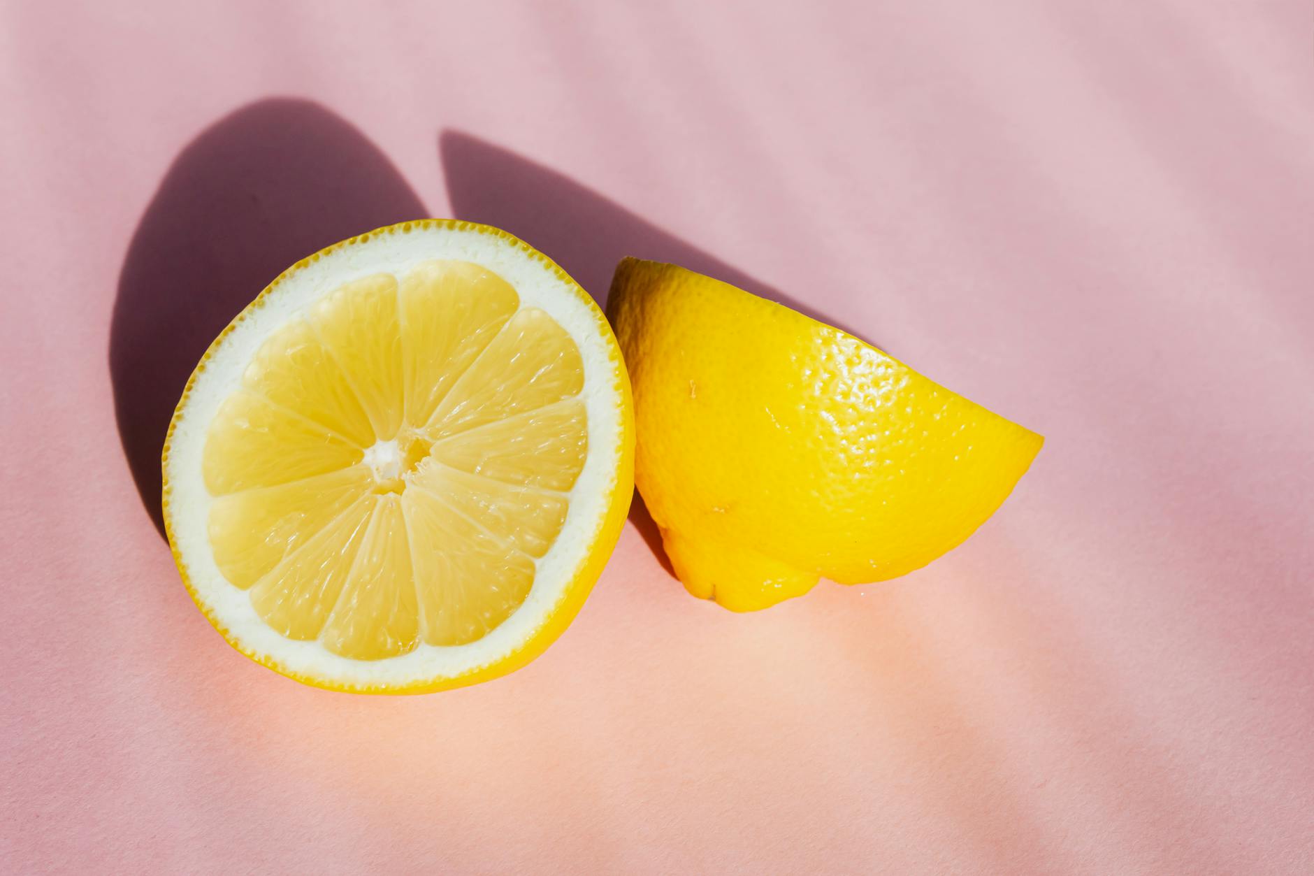 Fresh lemon halves on pink background in natural light, symbolizing freshness and exploration