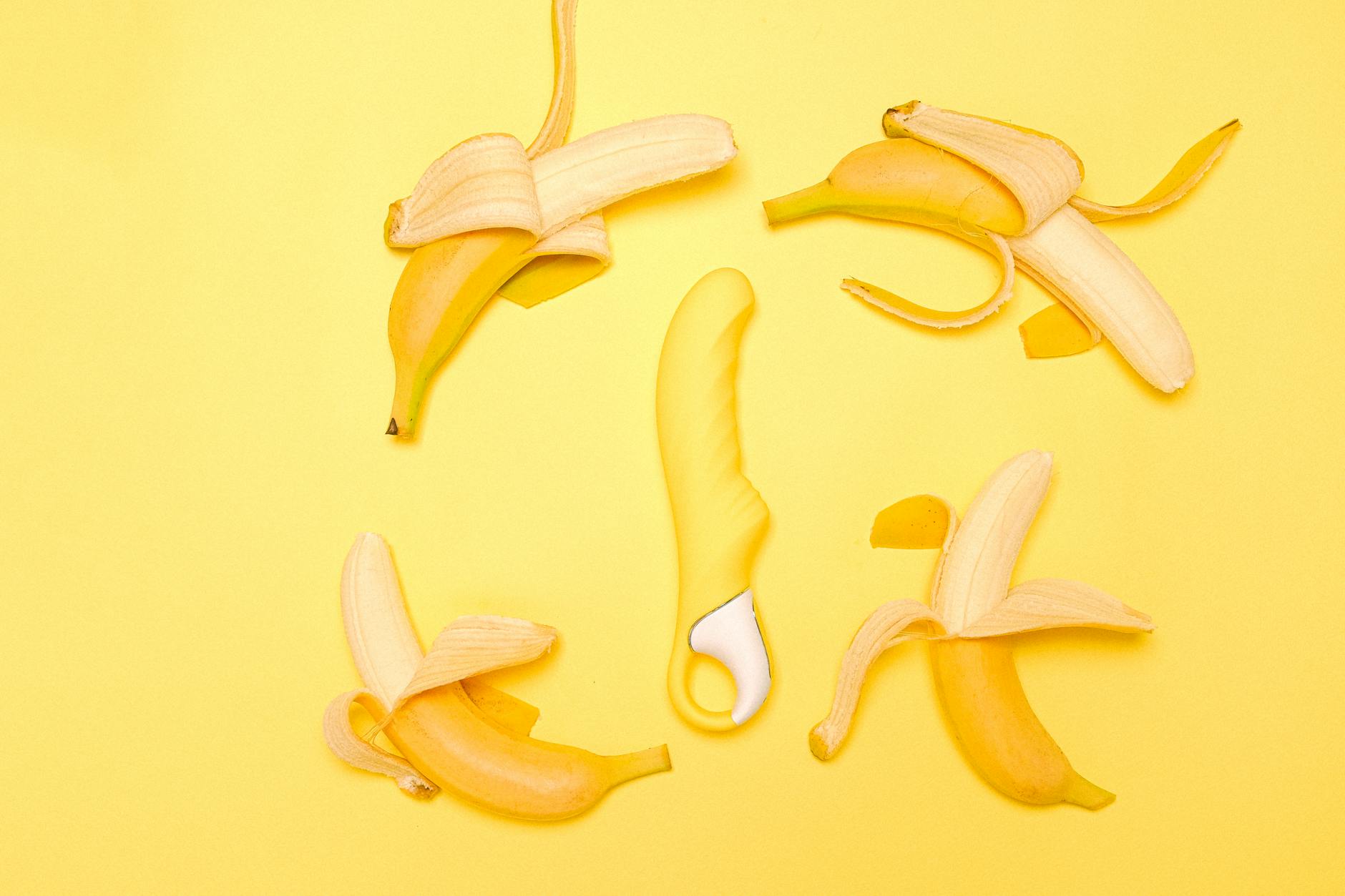 A bright yellow Lemon vibrator surrounded by fresh lemons on a warm yellow background
