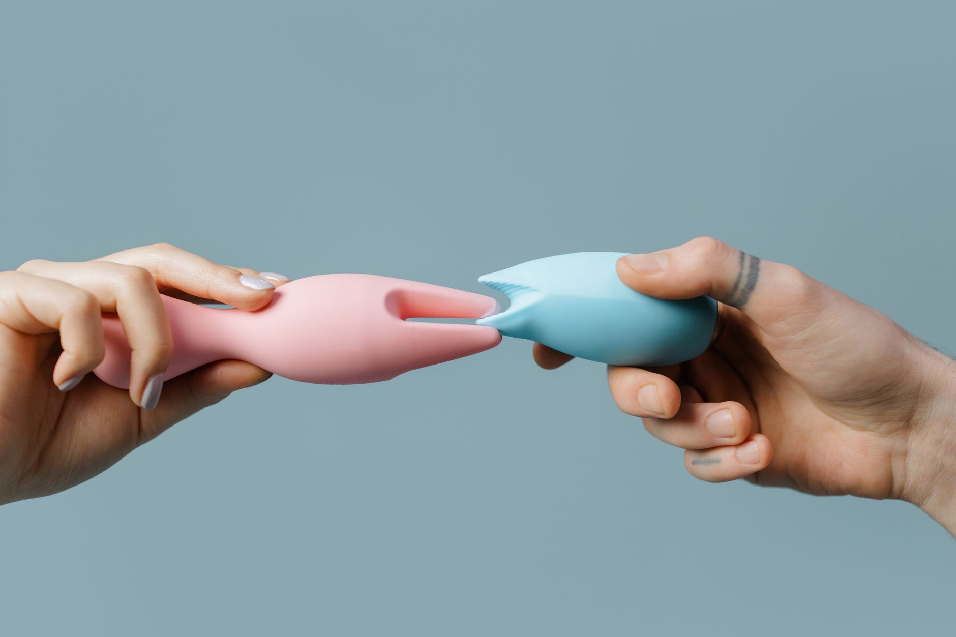Hands holding a sleek vibrator against a soft background, intimate and thoughtful