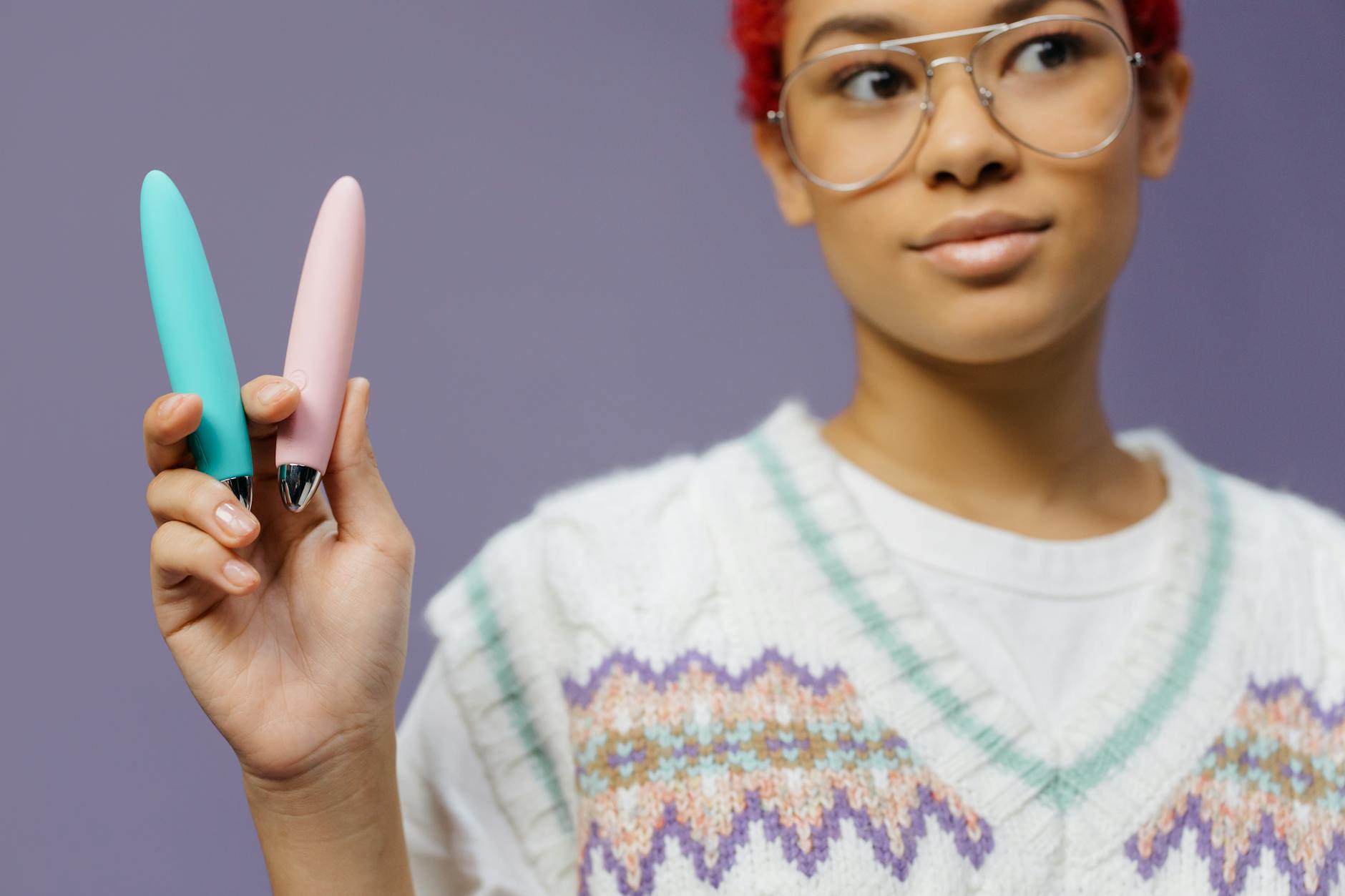 Blue silicone vibrator held in hand against purple background, promoting pleasure with protection