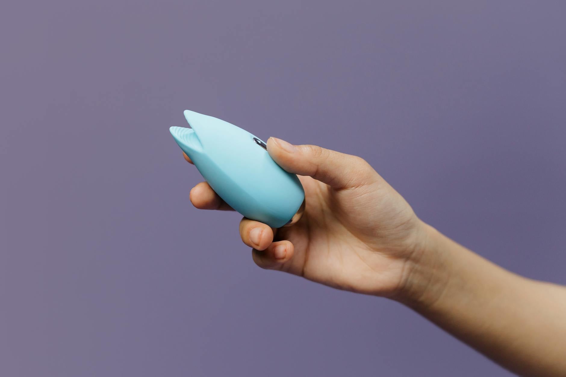 A vibrant lemon-colored clitoral vibrator held in hand, symbolizing pleasure and wellness for people managing endometriosis.