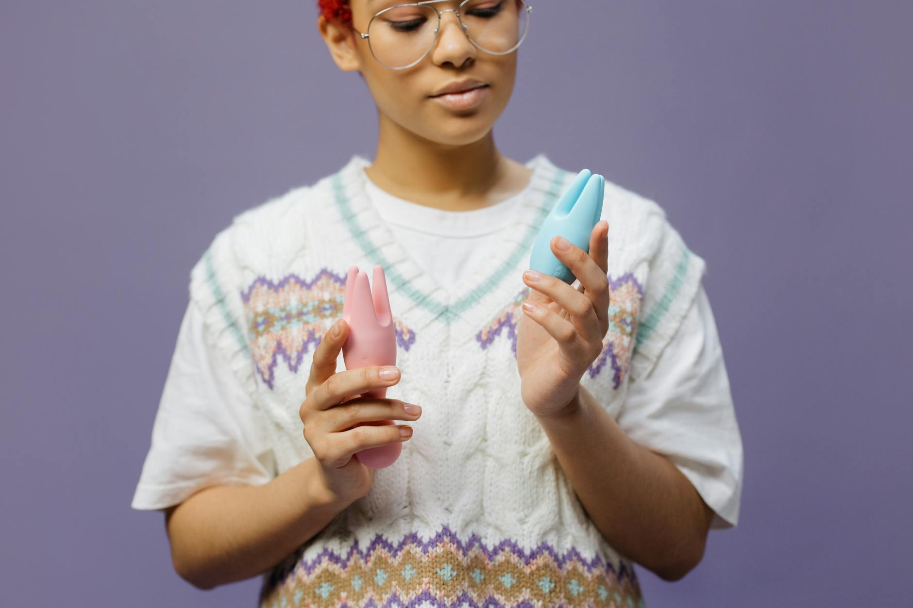 Woman thoughtfully holding a pink vibrator, representing vulnerability and intimate conversations with a partner